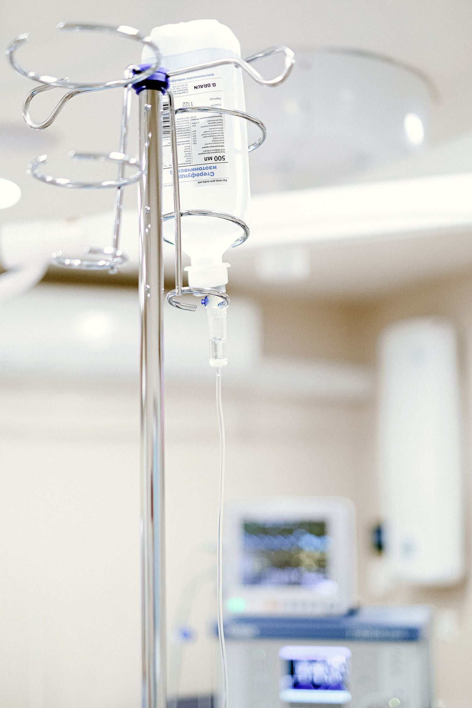 Real photograph of IV fluid bag and tubing on a stand in a clinical setting